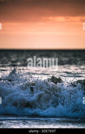Foamy waves rolling onto sandy shoreline along scenic coastal beach. Stock Photo