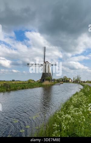 Historic windmill beside a calm canal in Kinderdijk, Netherlands ...