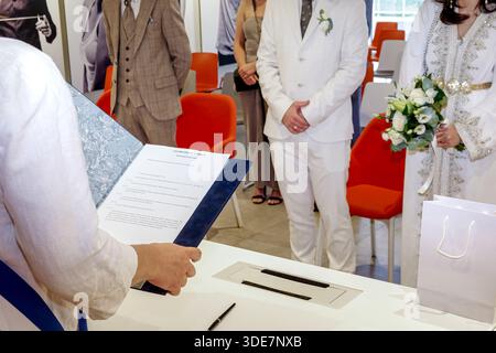 Civil wedding ceremony in a modern registry office as the officiant reads marriage documents before the bride and groom. Stock Photo