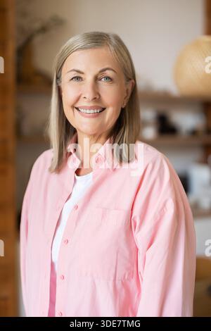 Mature woman standing in kitchen area with friendly smile Stock Photo