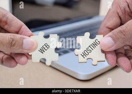 Hands holding two puzzle pieces labeled web and hosting. Website development, web hosting services, technology solutions concept. Stock Photo