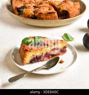 Slice of homemade plum pie on plate on light background. Stock Photo