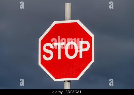 Red stop road sign against a dark sky in Ireland. Stock Photo