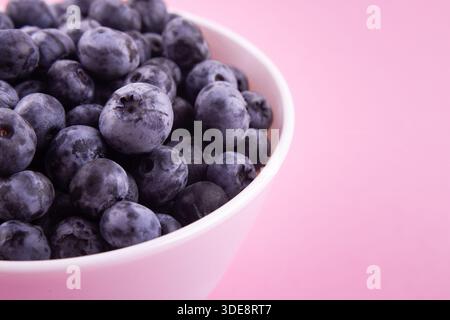 Blueberries on a macro scale. Dark berries in close-up. Ripe blueberries isolated on pink. Healthy, natural fruit. Stock Photo