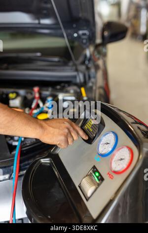 Mechanic checking the car air conditioning system using a technological diagnostic device. Stock Photo