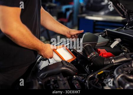 Hands of a mechanic replacing a car filter during professional engine maintenance service. Stock Photo