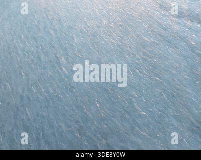 Aerial top view of a frozen sea surface with textured ice patterns and golden sunset reflections in winter, Estonia, Northern Europe. Stock Photo
