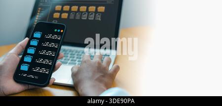 Close up of businessman hands holding smartphone and using laptop for digital document management system. Concept of cloud storage, database, paperles Stock Photo