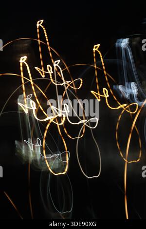 Cinematic panoramic view of golden light trails arching across a dark frame. A sleek, abstract representation of speed, data flow, and movement. Stock Photo