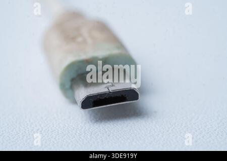Macro shot of a white micro USB plug. Concept for mobile phone charging, data transfer, and aging electronic accessories with worn texture. Stock Photo