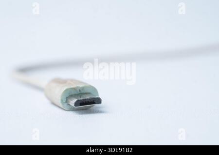 Macro shot of a white micro USB plug. Concept for mobile phone charging, data transfer, and aging electronic accessories with worn texture. Stock Photo