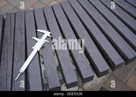 Caliper metal tool measuring equipment ruler on wooden bench background. Stock Photo