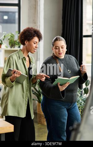 Two female managers collaborate and discuss while reviewing documents in a chic office. Stock Photo