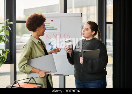 Two female managers have a thoughtful discussion in an office with presentation materials. Stock Photo