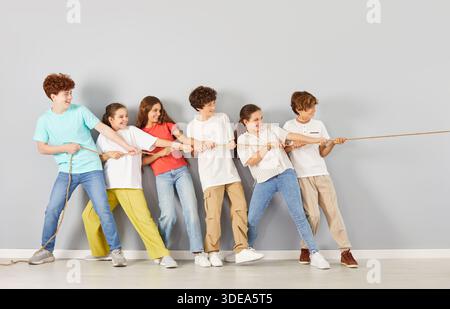 Students Pulling Rope Together On Grey Background Stock Photo
