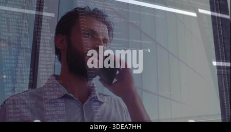 Standing man wearing light shirt talking on smartphone in office by glass wall with code overlay Stock Photo
