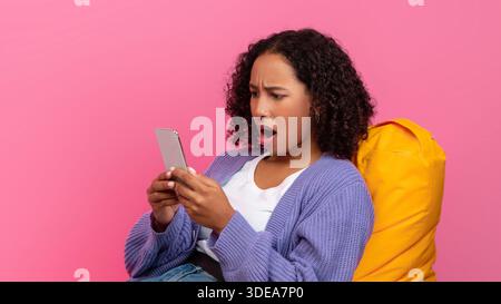 Young Woman Shows Surprise While Using Smartphone in Bright Setting Stock Photo