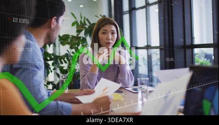 Listening center woman wearing purple sweater holding chin at meeting table, with green trend line Stock Photo