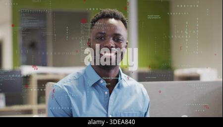 Smiling man in blue button-down shirt posing in open-plan office, with code overlays and cubicles Stock Photo
