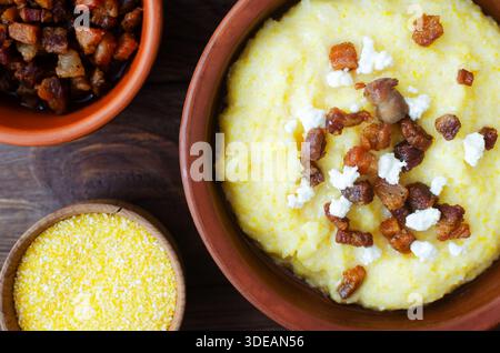 Classic banosh with bryndza and bacon slices in a decorative ceramic bowl on a wooden table. Traditional Ukrainian dish made from corn flour. Traditio Stock Photo