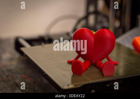 Red 3D printed heart on printer bed representing love and technology Stock Photo