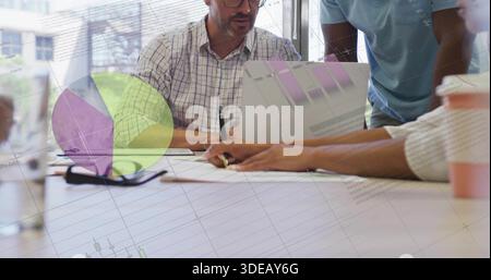 Three colleagues wearing button-up and t-shirt reviewing pie-bar charts in office, with glasses Stock Photo