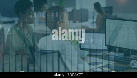 Working two women wearing business tops reviewing data on monitors at open office, chart overlay Stock Photo