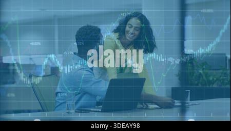 Leaning yellow-top woman engaging seated blue-shirt man in office laptop papers charts-overlay Stock Photo