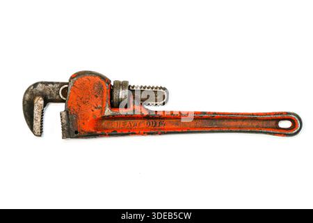 Old heavy duty pipe wrench with chipped red paint, isolated on white background. Rugged adjustable hand tool for plumbing, repair, and industry Stock Photo