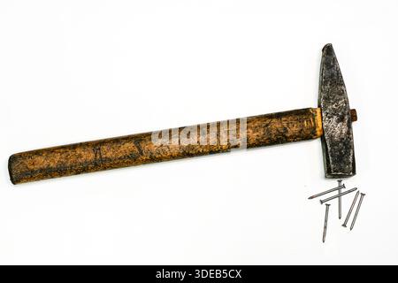 Vintage carpenter hammer with worn wooden handle and scattered steel nails on white background. Classic hand tool symbolizing repair and craftsmanship Stock Photo