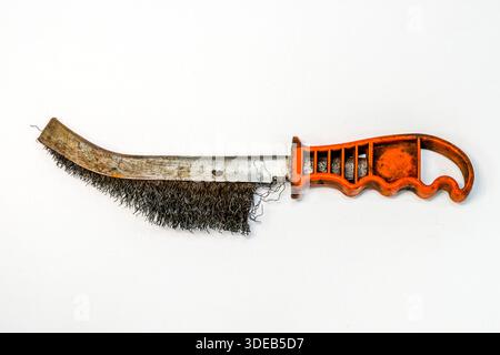 Old curved wire brush with worn steel bristles and orange plastic handle, isolated on white. Hand tool for rust removal, cleaning metal and surfaces Stock Photo