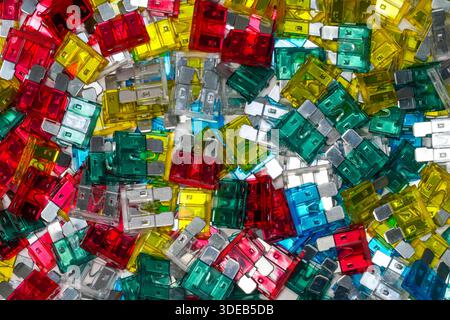 Close-up of assorted automotive blade fuses in red, yellow, green and blue. Electrical protection components forming a colorful abstract background Stock Photo