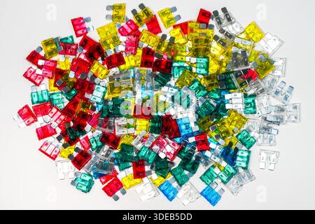 Top view of mixed automotive blade fuses in red, yellow, green, blue and clear colors. Electrical safety components arranged as a colorful pile Stock Photo