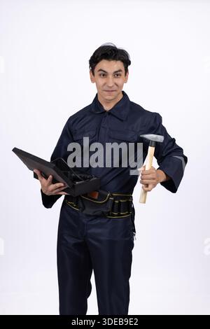 Young repairman in uniform holding tools and a clipboard. Stock Photo