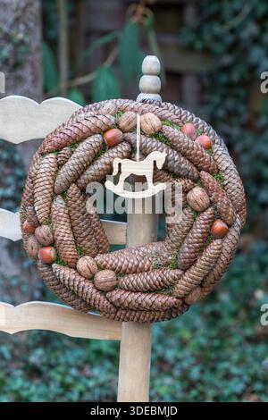 wreath made of spruce cones, walnuts and hazelnuts on a garden chair Stock Photo
