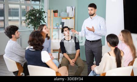 Male teacher talking to interested students sitting in a circle Stock Photo