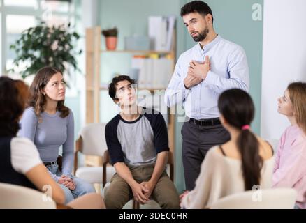 Male teacher talking to interested students sitting in a circle Stock Photo