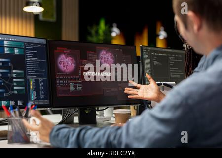 Close up of system administrators in office trying to fix hacking attempt on corporate network. Tech startup coworkers investigating unauthorized access alerts, brainstorming ways to mitigate damages Stock Photo