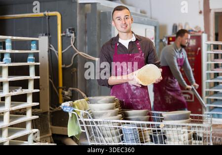 Successful potter displaying handcrafted plate in artisanal studio Stock Photo