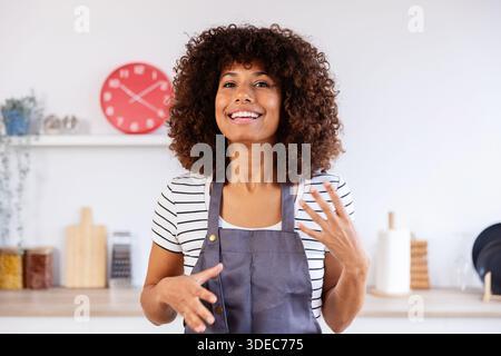 POV of smiling young woman talking to the camera explaining recipe in kitchen Stock Photo