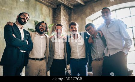 A diverse group of business men standing together in a modern office, smiling and showing strong teamwork, confidence, and an inclusive workplace atmo Stock Photo