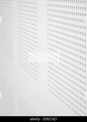 White perforated acoustic panel texture with seamless geometric pattern on soundproofing wall in modern studio offering minimal abstract background an Stock Photo
