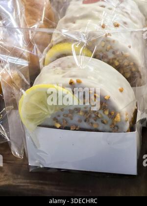 Delicious creamy white glazed lemon cake with nut toppings inside clean plastic package showing sweet appetizing feeling for homemade dessert snack ti Stock Photo