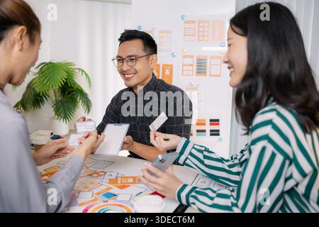 A group of UX/UI designers brainstorming creative ideas together, discussing color palettes and layout concepts for a new mobile application interface Stock Photo