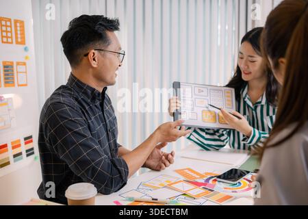 Designers having a UX/UI planning meeting to refine mobile app layouts and user flow. They collaborate closely to create functional and visually appea Stock Photo