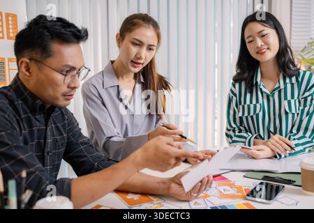 Designers having a UX/UI planning meeting to refine mobile app layouts and user flow. They collaborate closely to create functional and visually appea Stock Photo