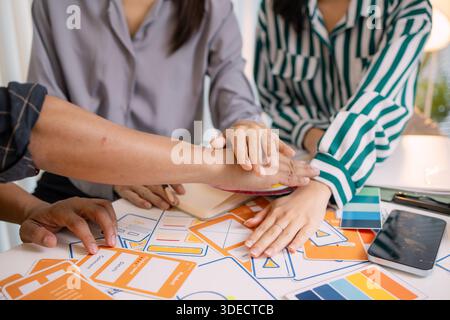 Designers having a UX/UI planning meeting to refine mobile app layouts and user flow. They collaborate closely to create functional and visually appea Stock Photo