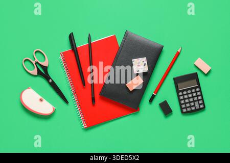 Different rubber erasers with notebooks and stationery on green background Stock Photo