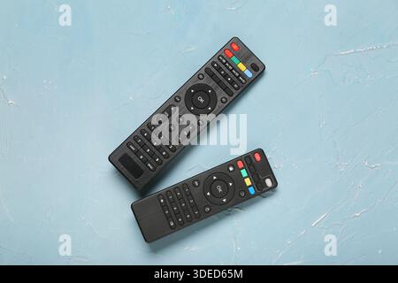 Different modern TV remote controls on blue grunge background Stock Photo