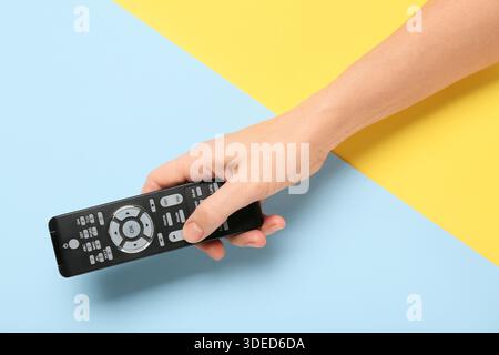 Female hand with TV remote control on color background Stock Photo